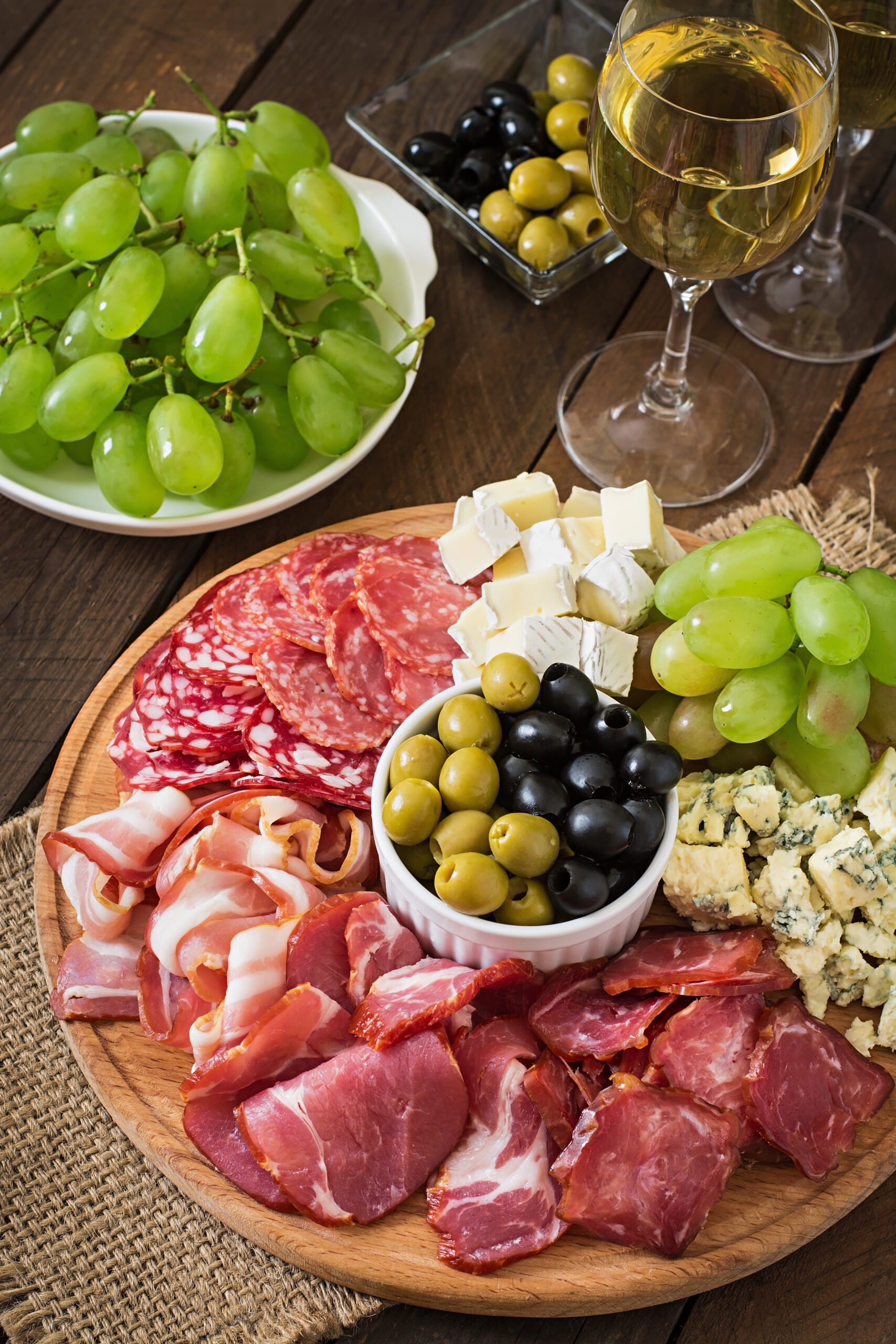 plateau-de-restauration-antipasto-avec-bacon-saccade-salami-fromage-et-raisins-sur-une-table-en-bois Antipasto catering platter with bacon, jerky, salami, cheese and grapes on a wooden background